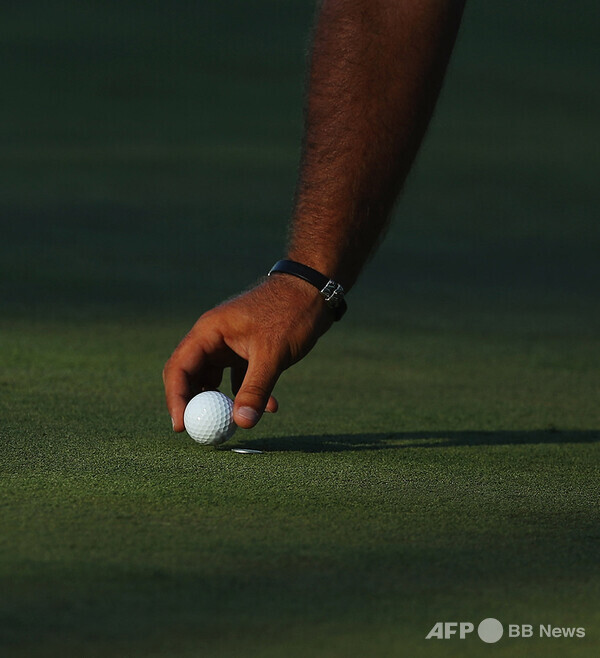 한 골프 선수가 그린 위에 마크를 하고 공을 집고 있다. 사진제공=ⓒAFPBBNews = News1